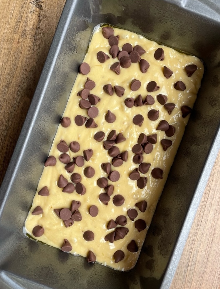 Yellow cake mix banana bread in a bread pan with chocolate chips on top, ready for baking. 