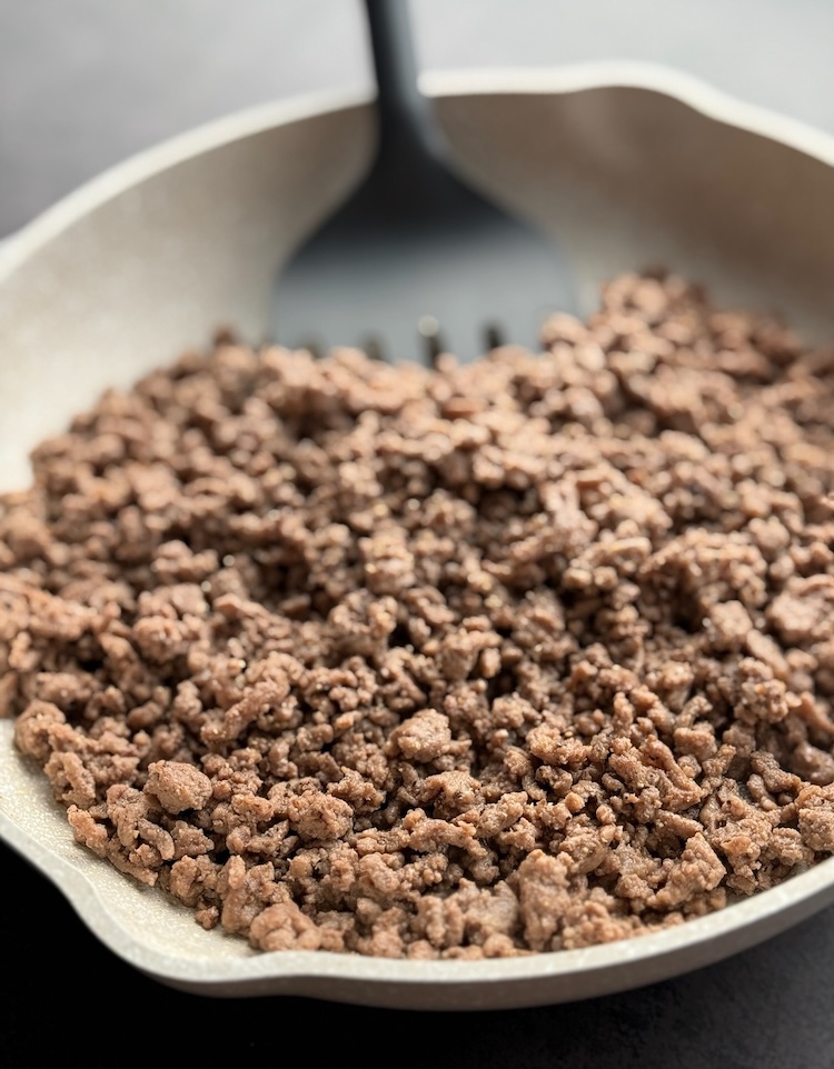 Chopped and browned ground beef in a pan ready to mix into the casserole.