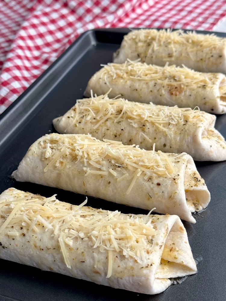 Delicious pizza burritos stuffed full of lots of gooey cheese, pepperoni, pizza sauce, and all of your favorite toppings. They are brushed with garlic butter and topped with shredded parmesan to make yummy handheld food for dinner. 