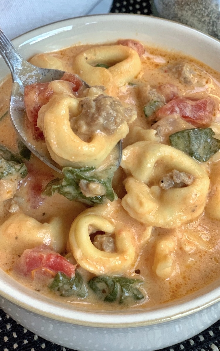 Close up view of a yummy slow cooker soup recipe made with cheese tortellini and ground sausage. 