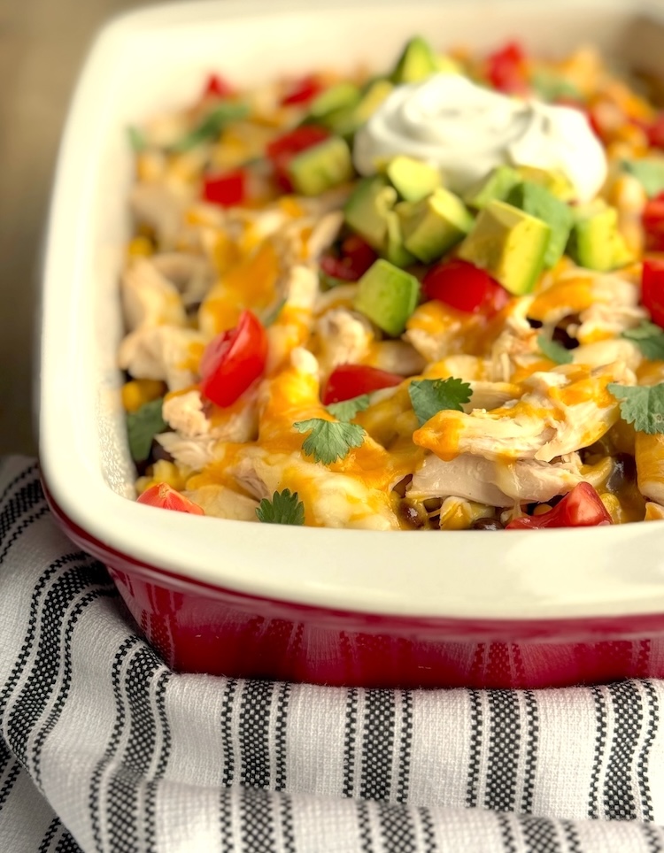 Yummy dinner casserole for a large family made with simple and cheap ingredients including Mexican rice, chicken, salsa, sour cream, beans, and corn. Customize this easy weeknight dinner with all of your favorite taco toppings. 