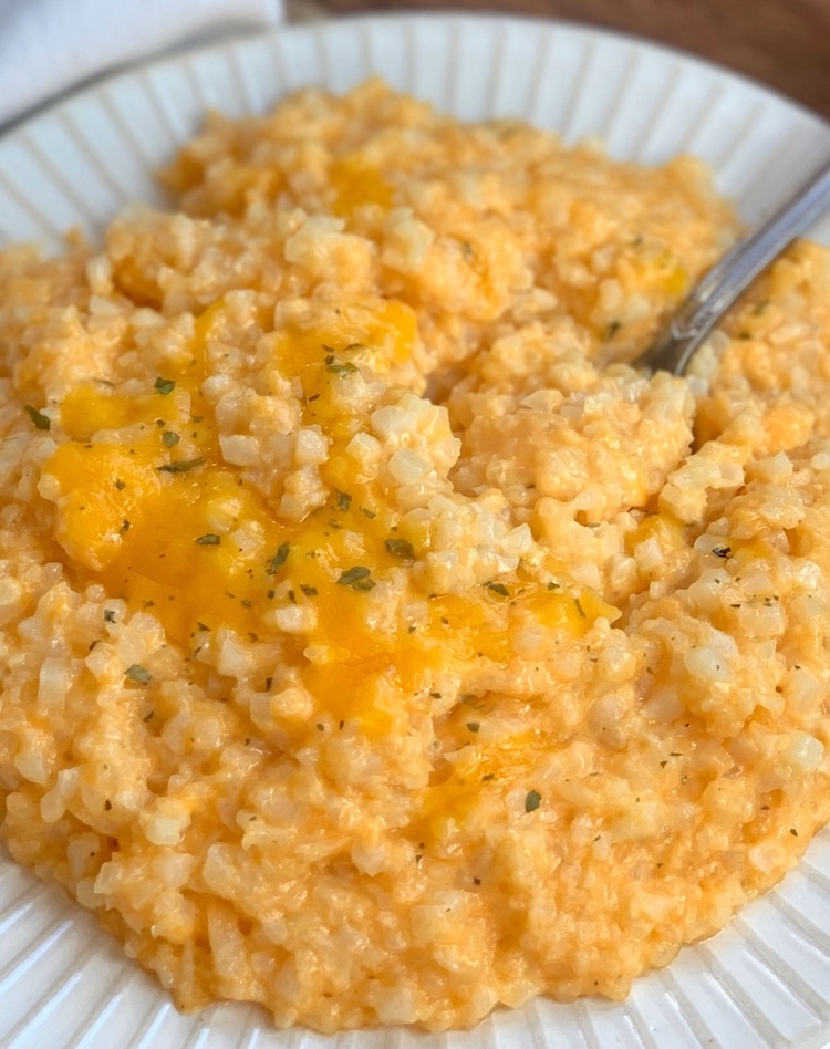 Close up view of a delicious vegetable side dish made with frozen cauliflower rice, cheddar, cream cheese, and seasoning. 